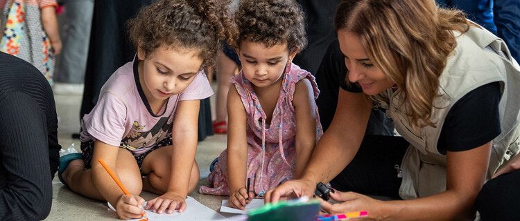 UNICEF medewerker speelt op de grond met twee meisjes